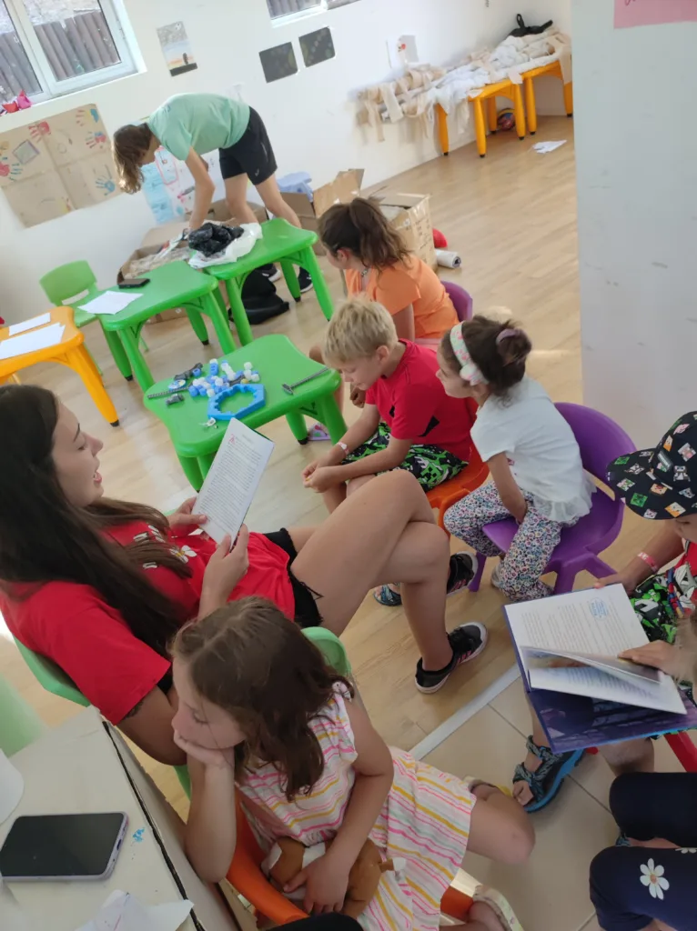 Деца и аниматорка четат книжки в детския клуб